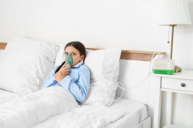 Yatak odasında nebulizör kullanan tatlı kız.