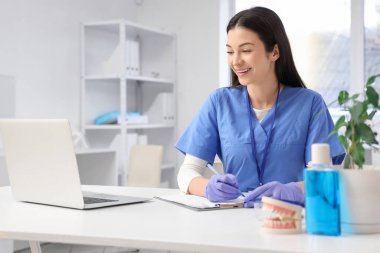 Klinikteki masada çalışan genç bir dişçi.