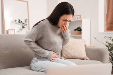 Evdeki kanepede hasta yatan genç bir kadın.