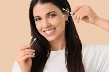 Bej arka planda pamuk tomurcukları olan güzel bir kadın, yakın plan.