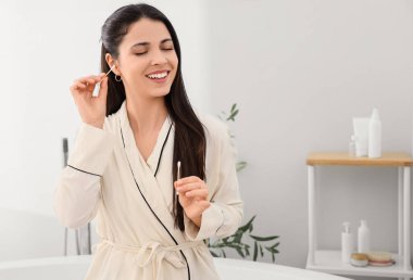 Banyoda pamuklu tomurcukla kulakları temizleyen güzel bir kadın.