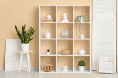 Beyaz raf ünitesi ve bitkileriyle oturma odasının içinde.