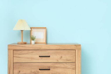 Mavi duvarın yanındaki klozette bitkisel ve boş çerçeveli lamba