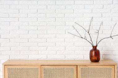 Beyaz tuğla duvarın yanında klozette ağaç dalları olan vazo