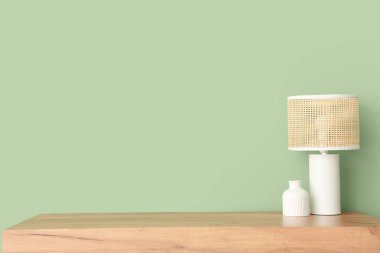 Yeşil duvarın yanındaki klozette vazo olan lamba