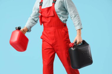 Mavi arka planda yürüyen teneke kutuları olan erkek tamirci