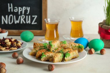 Geleneksel baklava, fındık ve çay tabağı beyaz masada, yakın plan. Nowruz Bayram kutlaması