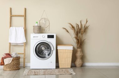 Çamaşır makinesi, sepet ve merdiveni olan modern ev çamaşırhanesi.