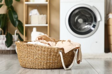 Çamaşır sepetinde kirli çamaşırlar ve çamaşır makinesi.