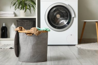 Çamaşır odasında çamaşır makinesinin yanında kirli çamaşırlarla dolu sepet.