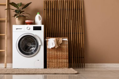 Çamaşır odasında kirli çamaşırları olan modern çamaşır makinesi, merdiven ve sepet.