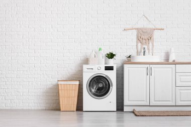 Modern çamaşır makinesi, çamaşır sepeti ve banyo lavabosu olan çekmeceler.