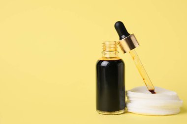 Sarı arka planda iyot, pipet ve pamuk pedleri olan şişe, yakın plan.