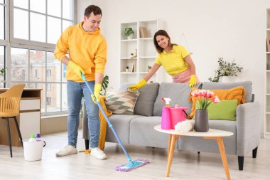 Genç çift bahar günü odayı temizliyor.