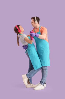 Kulaklıklı önlüklü genç bir çift leylak arka planda dans ediyor.