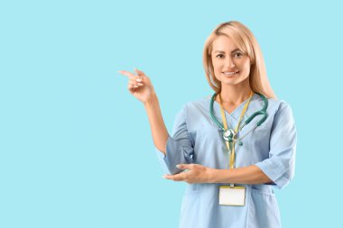 Güzel doktor mavi arka plandaki bir şeyi işaret ediyor.