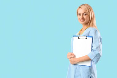Mavi arka planda boş panosu olan güzel bir doktor.
