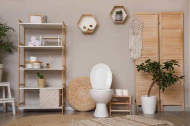 Tuvaletin içinde klozet, katlanan ekran ve raf ünitesi olan bir oda.