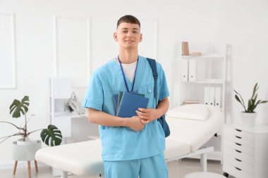 Klinikte sırt çantası ve not defterleri olan bir erkek stajyer.