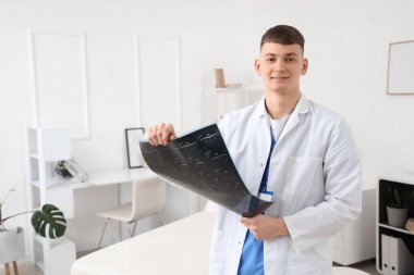 Erkek tıp stajyeri klinikte röntgen taraması okuyor.