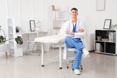 Klinikteki taburede oturan erkek stajyer.