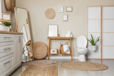 Interior of restroom with toilet bowl, table and folding screen