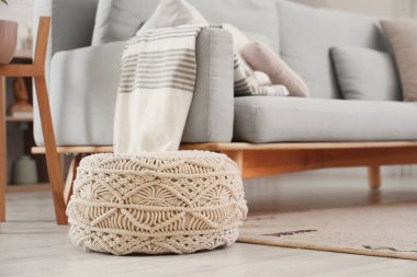 Oturma odasındaki kanepenin yanında örülmüş puf, yakın plan.