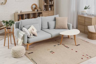 Gri kanepe, masa ve raf ünitesi olan oturma odasının içinde.