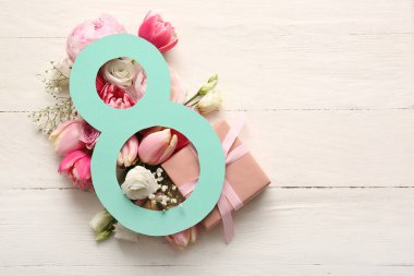 Beyaz ahşap zemin üzerinde güzel çiçekler ve hediye kutusu olan kağıttan yapılmış 8 figür. Uluslararası Kadınlar Günü kutlamaları