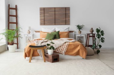 Büyük yataklı, masalı ve bitkilerli rahat bir yatak odası.