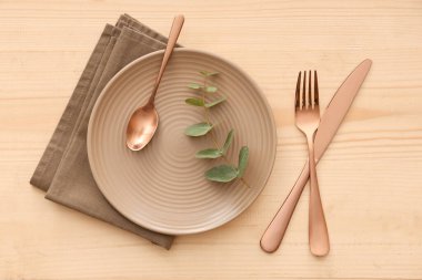 Tabak, çatal bıçak, peçete ve okaliptüs dallı şık masa seti.