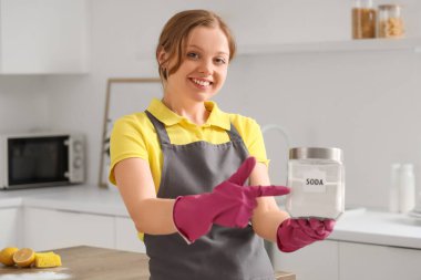 Mutfakta bir kavanoz kabartma tozu temizleyen genç bir kadın.