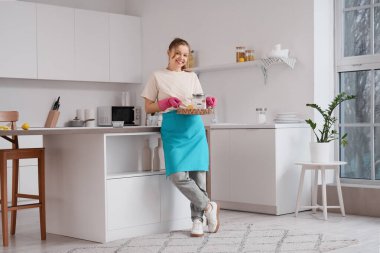 Genç ev hanımı elinde kabartma tozu ve limonla mutfakta tepsi tutuyor.