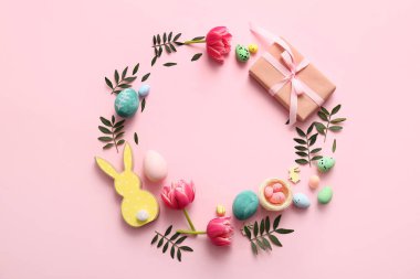 Paskalya yumurtalarından, hediye kutusundan, çiçeklerden, yeşil yapraklardan ve pembe arka planda dekordan yapılmış çerçeveler.