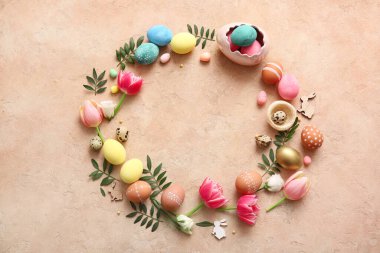 Paskalya yumurtaları, çiçekler, yeşil yapraklar ve bej rengi grunge arka planda dekordan yapılmış çerçeve