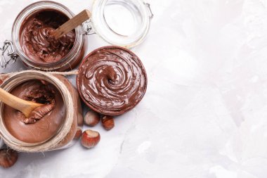 Bir kâse dolusu lezzetli çikolata ve arkaplanda fındıklar var.