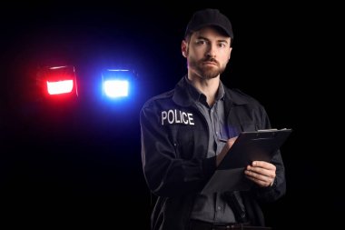 Siyah arka planda yanıp sönen siren ışıklarına karşı panoya yazı yazan erkek polis memuru