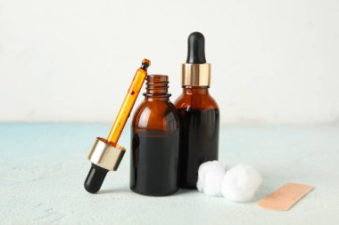 Tentürdiyot, pipet, pamuk topları ve açık mavi masada tıbbi alçı bulunan şişeler.