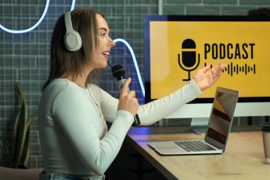 Stüdyoda kulaklığı ve mikrofonu olan genç bir kadın podcast yapıyor.