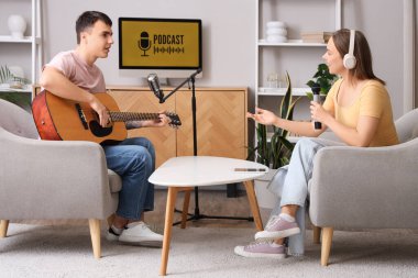 Stüdyoda Podcaster ile gitar çalan genç adam.