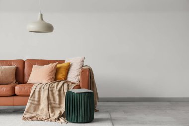 Oturma odasının içinde kahverengi deri kanepe ve pouf 'ta dizüstü bilgisayar var.