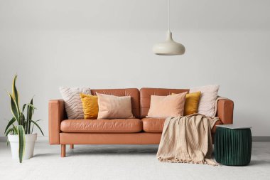 Kahverengi deri koltuklu, çiçekli ve laptoplu oturma odasının içi.