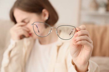 Evinde yeni gözlükleri olan güzel, yorgun bir kadın.