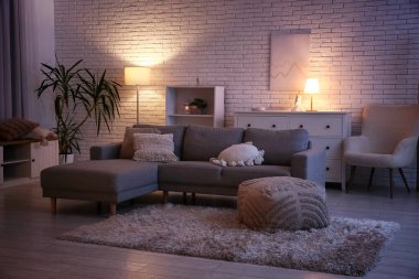 İçinde kanepe, puf ve parlayan lambalar olan karanlık bir oturma odası.