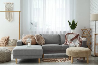 Pencerenin yanında puf ve kanepe olan aydınlık oturma odasının içinde.