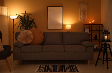 Kanepesi ve bej duvarın yanında parlayan lambaları olan karanlık oturma odasının içinde.