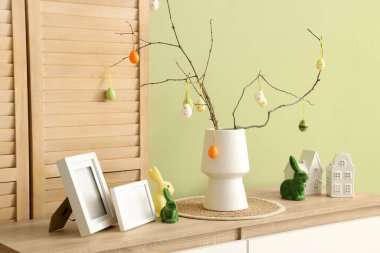 İçinde ağaç dalları olan vazolar ve şenlikli oturma odasındaki çekmecelerin üstünde paskalya yumurtaları, yakın plan.