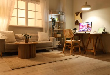 Akşamları şık oturma odasındaki masada bilgisayar oyunu oynuyor.