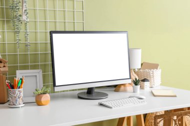 Yeşil duvarın yanında modern bilgisayarlı şık çalışma alanı, yakın plan.