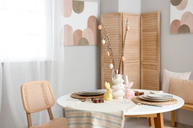 Ağaç dallı vazo ve Paskalya yumurtaları şenlikli yemek odasında servis edilen masada, yakın plan.